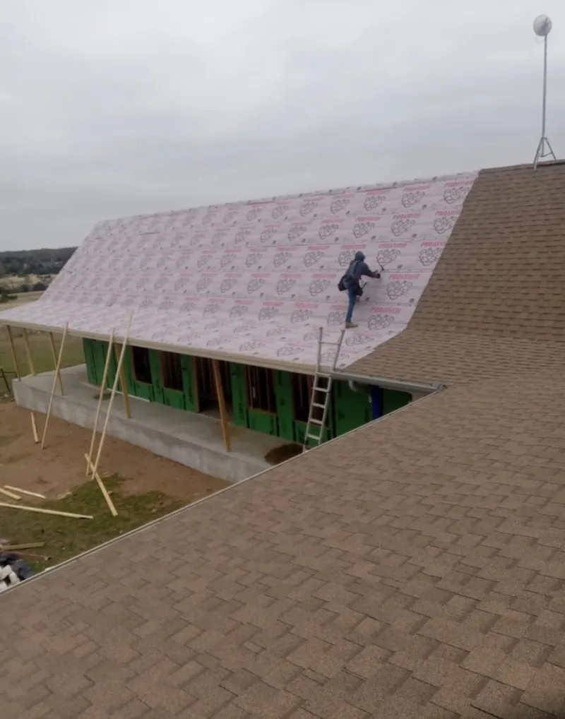 Worker preparing underlayment for a metal roof installation in Fortuna